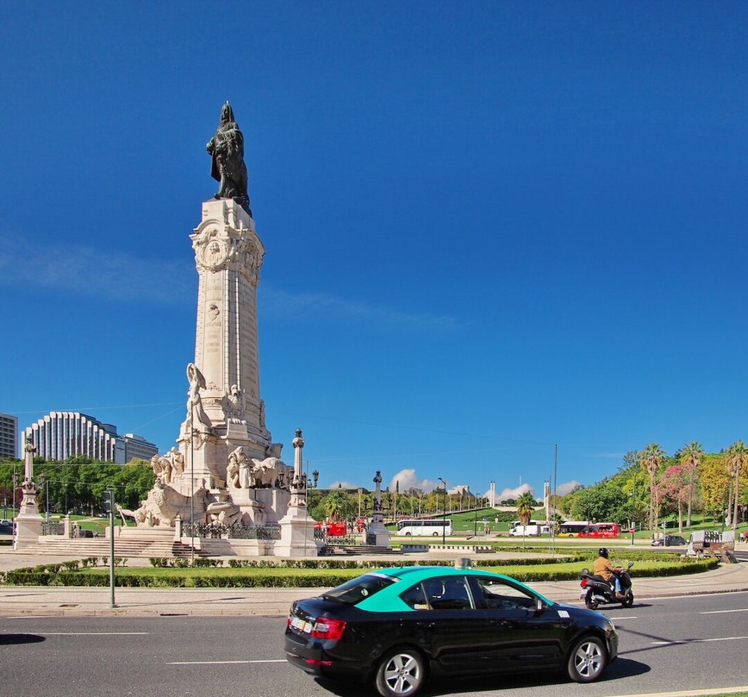 The Marquis de Pombal Statue with Parque Eduardo VII in the background. In the foreground, a typical green and black Portuguese taxi stands out.