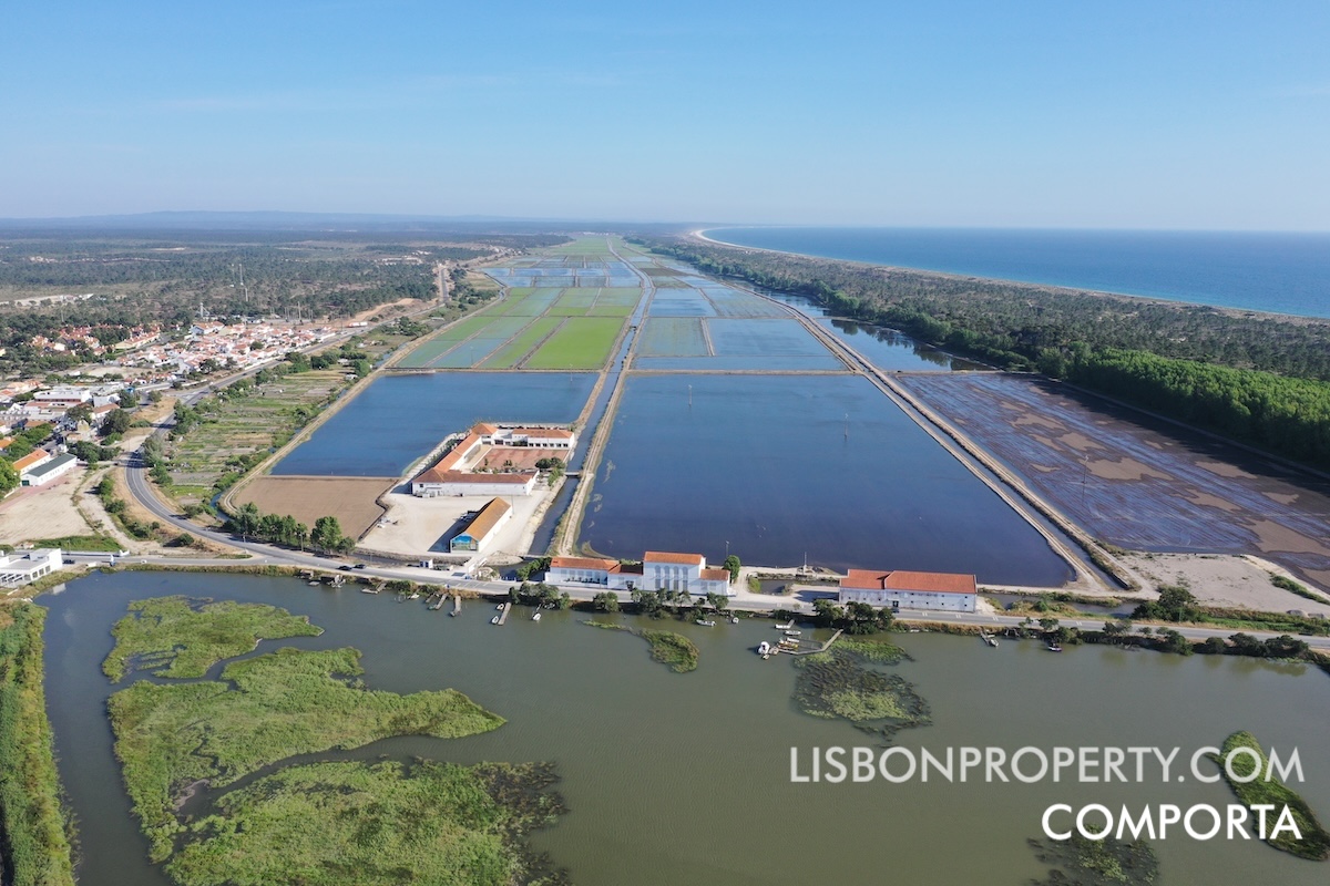 Photo of Comporta village on the left side. The Rice Museum building is visible in the foreground. Rice fields stretch for about 8 kilometers (approximately 5 miles) toward Lagoa Formosa and Carvalhal. Dunes and a beach can be seen on the right side of the image.